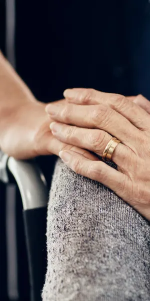Two hands resting, one with a wedding ring.