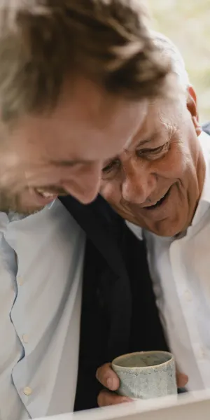 Two men sharing a joyful moment, holding a cup.