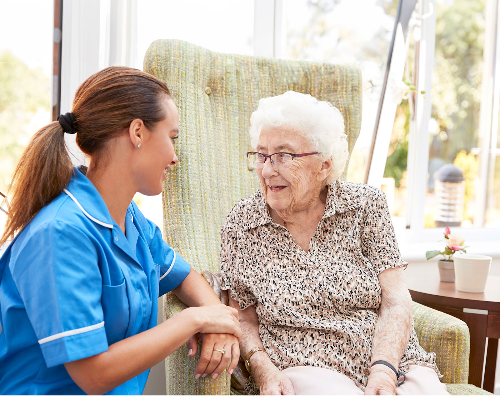 Caregiver and elderly woman sharing a warm conversation indoors.